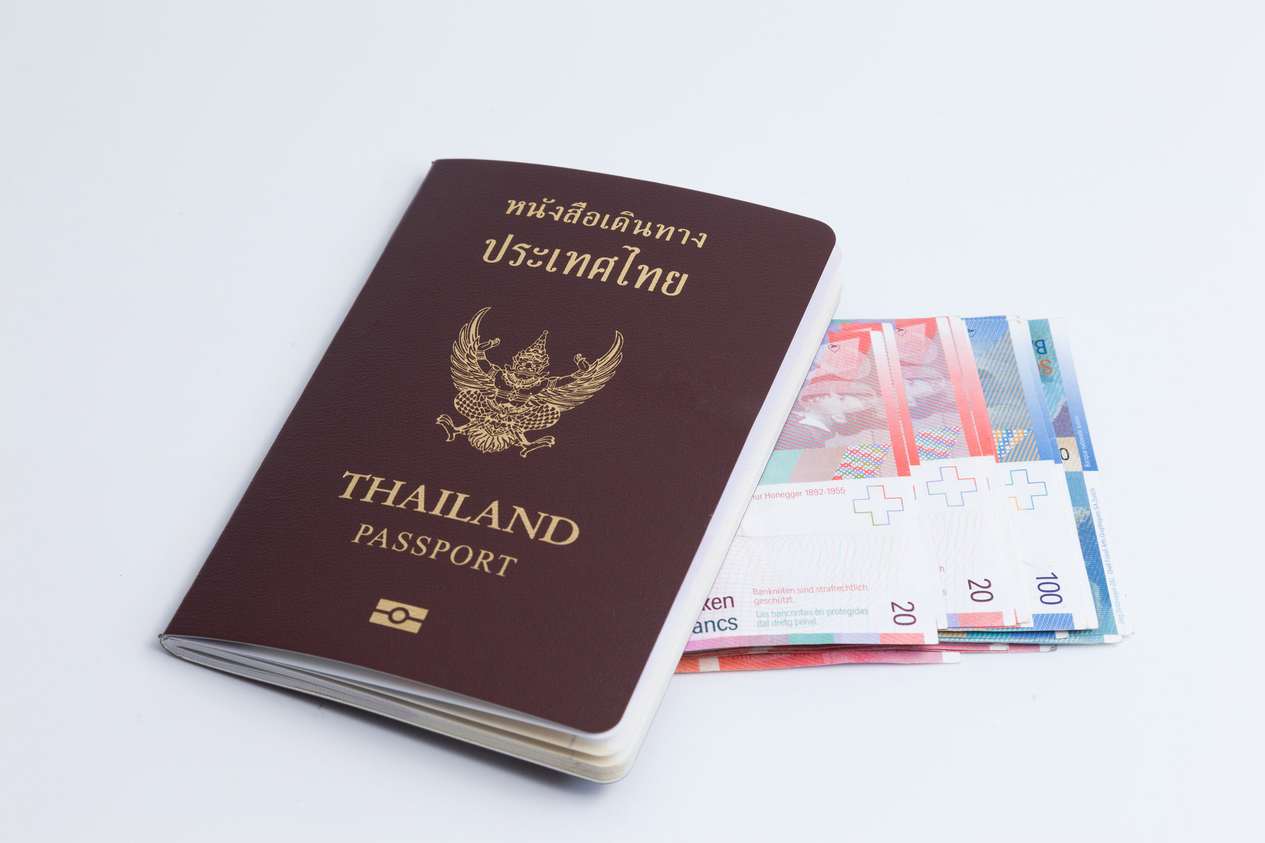 หนังสือเดินทางไทยพร้อมธนบัตรเงินฟรังก์สวิสที่วางอยู่ด้านใน